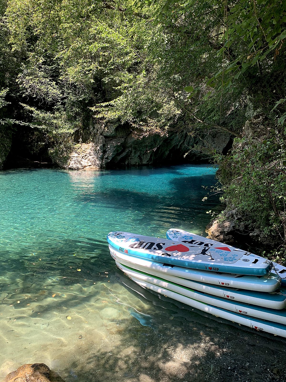Una canoa ferma sull'acqua turchese di una gola stretta, fra le rocce e gli alberi